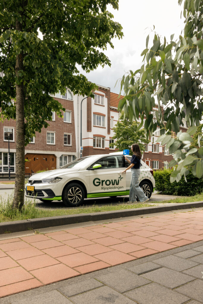 Leerling stapt in bij lesauto van Grow Rijopleidingen in een woonwijk